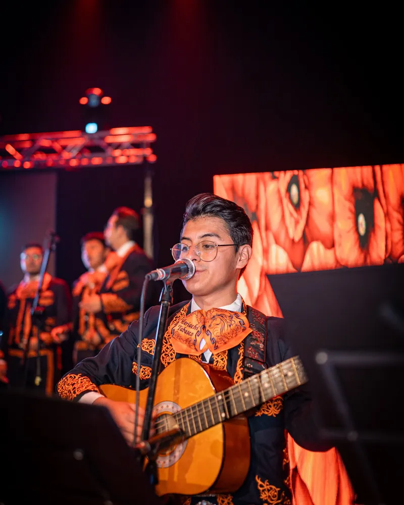 Músico de Mariachi Tabasco cantando con su guitarra en el escenario